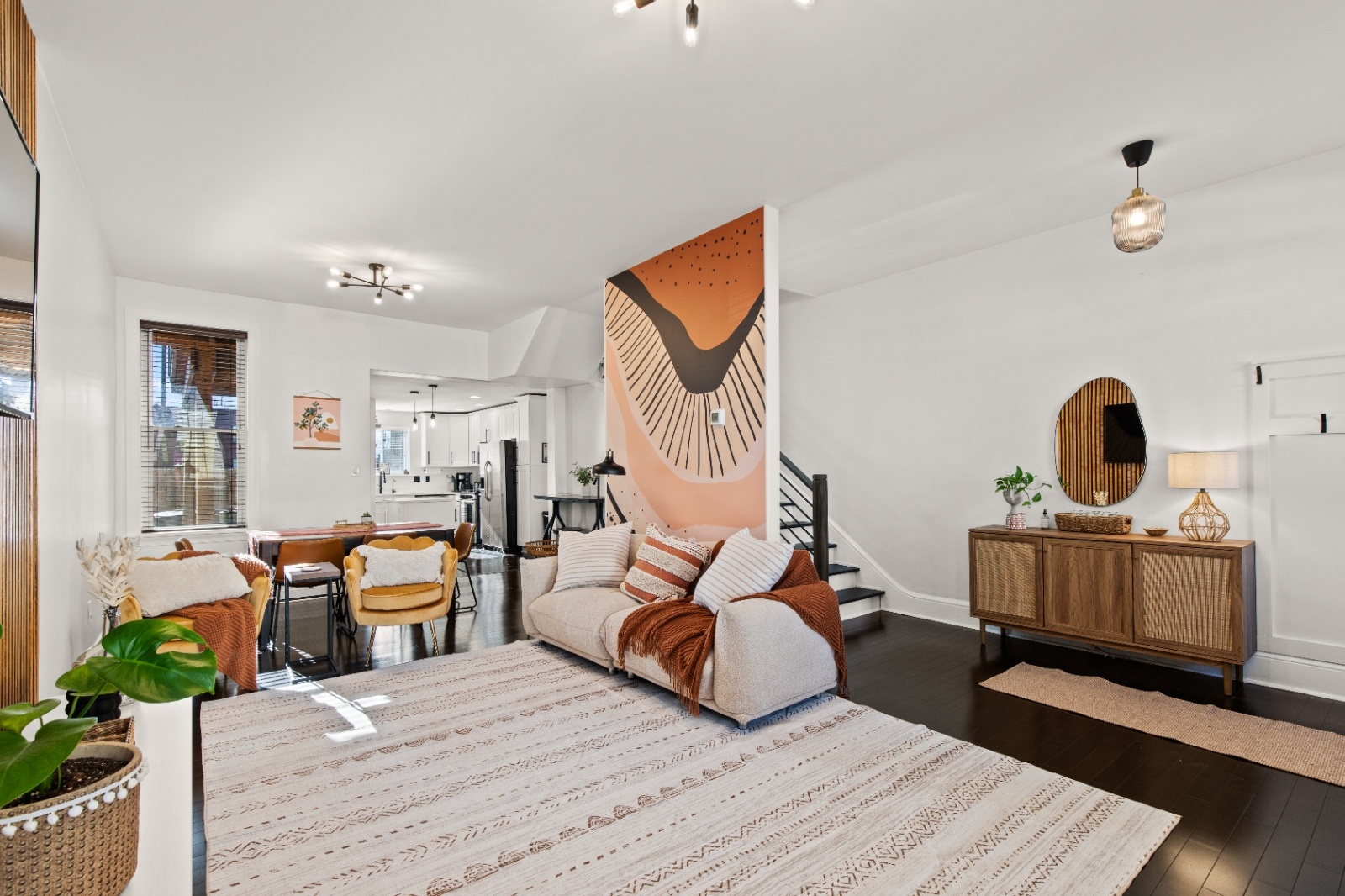 Open concept living room at Luxury on Lemon Airbnb in Lancaster, PA with abstract mural wall, cozy seating, and modern decor.