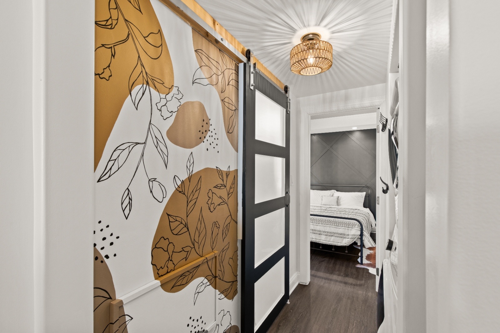 Decorative hallway at Luxury on Lemon Airbnb in Lancaster, PA with abstract mural wall and modern sliding barn door leading to bedroom.
