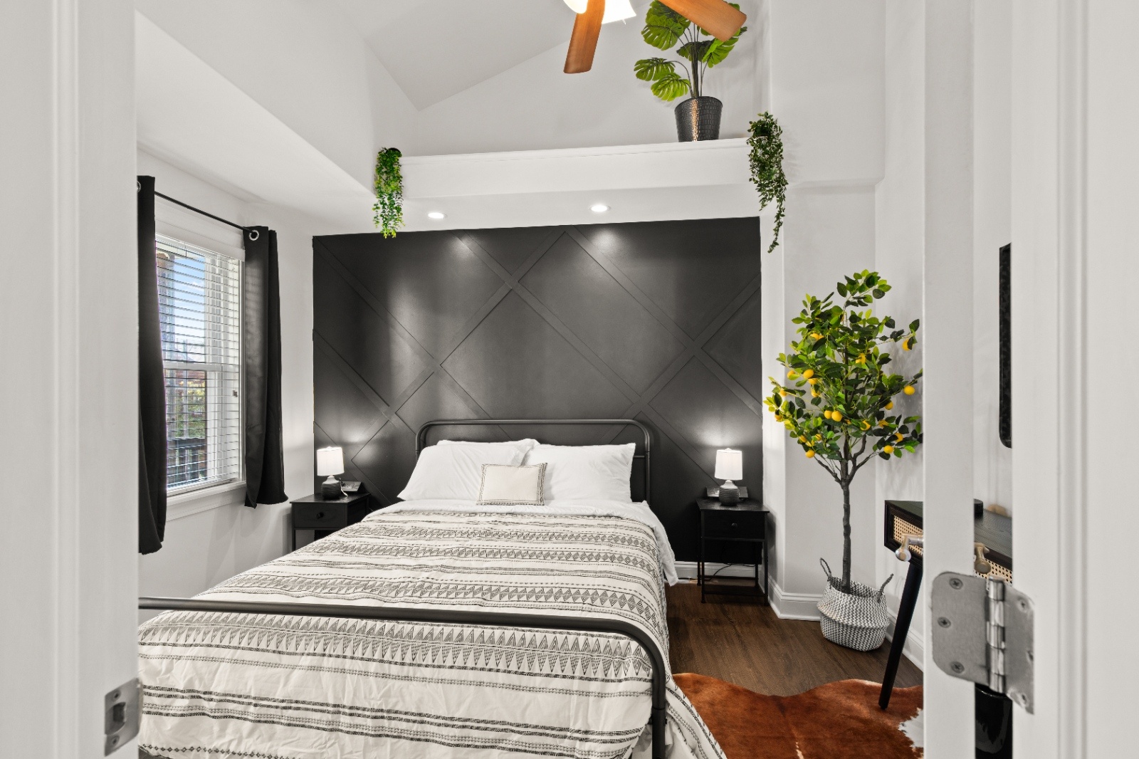 Modern king bedroom at Luxury on Lemon Airbnb in Lancaster, PA featuring a black accent wall, cozy bedding, bedside lamps, and stylish decor.