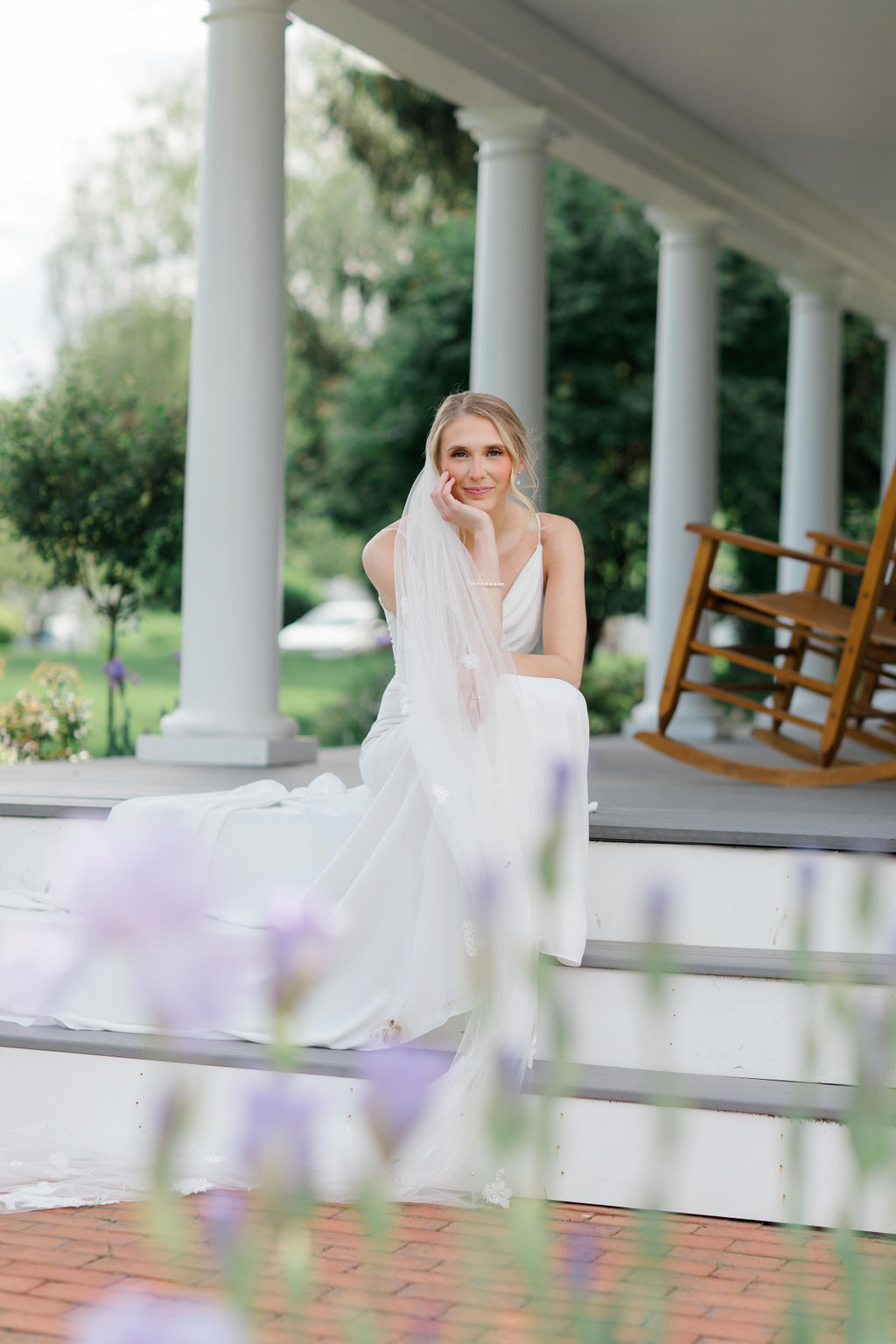 Bride posing on the steps with her hand in her chin and veil draped over shoulder