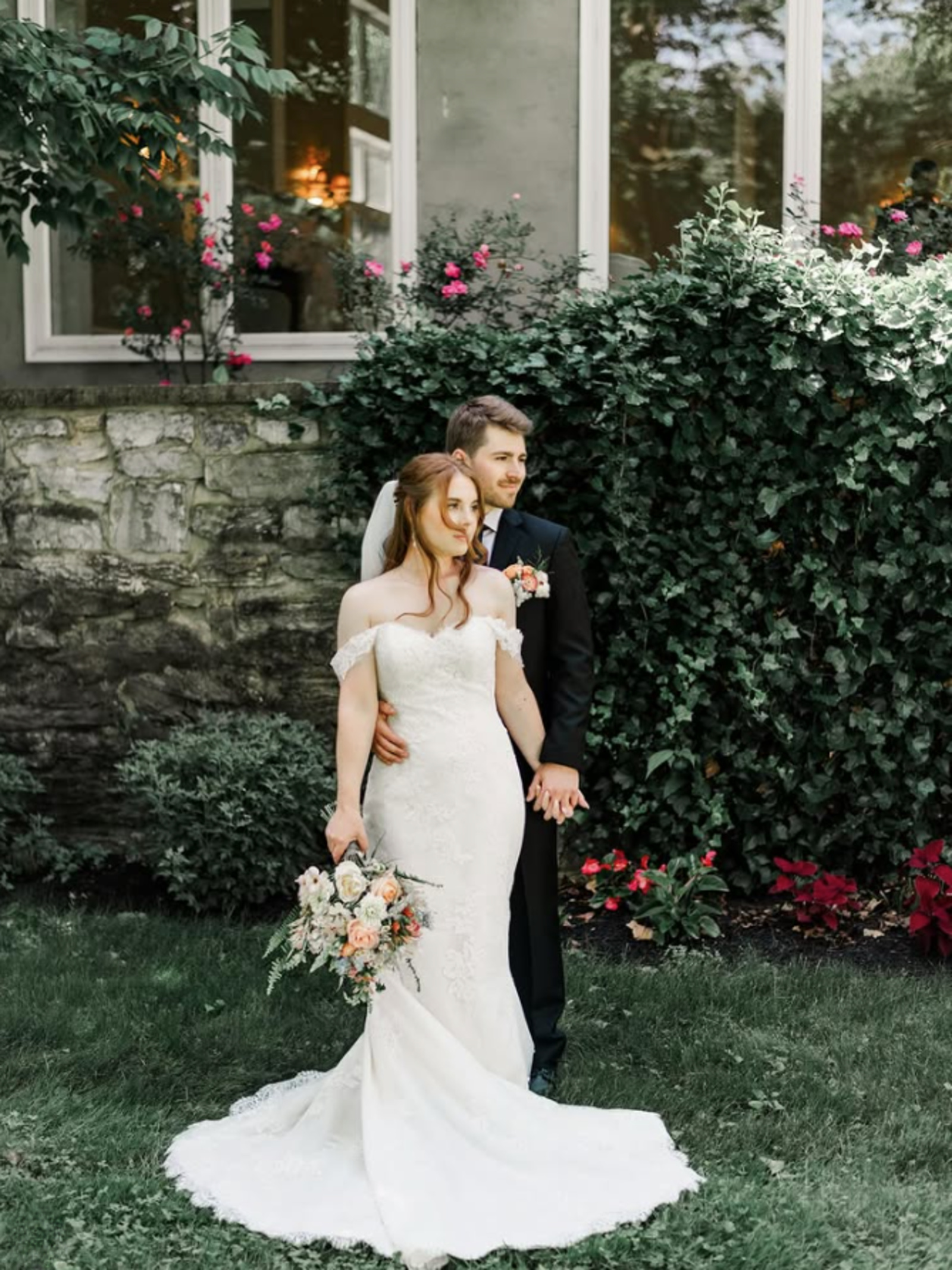 Bride and groom posing in front of ivy-covered stone wall at a garden wedding venue in Lancaster PA