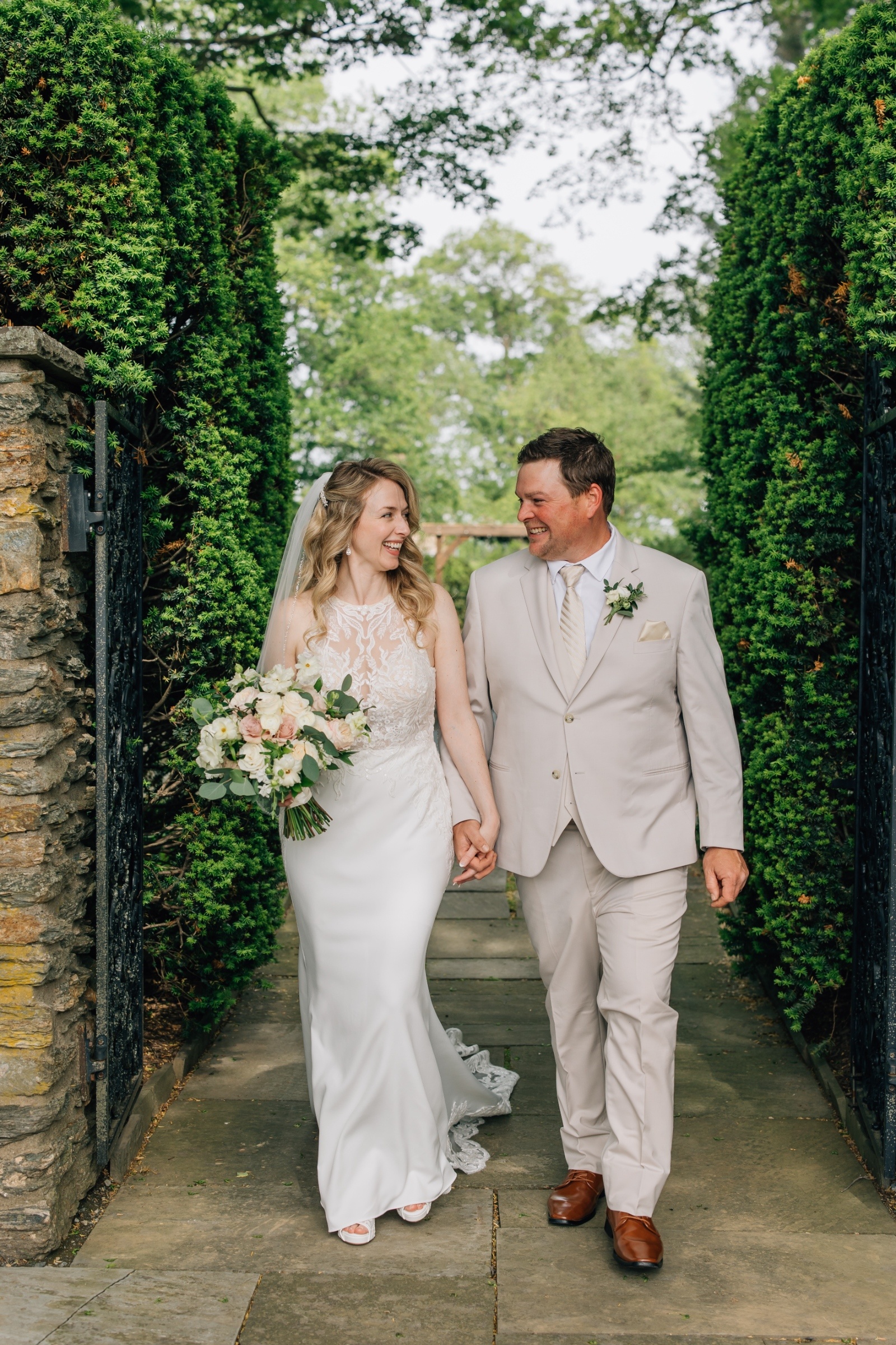 Bride and groom walking through lush gardens at Drumore Estate wedding venue in Pequea Pennsylvania