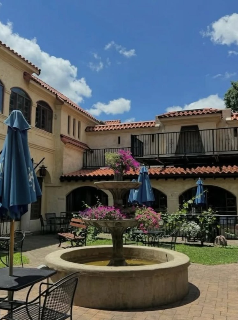 El Serrano Courtyard in Lancaster, PA Outdoor courtyard at El Serrano in Lancaster, PA, featuring a central fountain, patio seating, colorful flowers, and Mediterranean-style architecture.