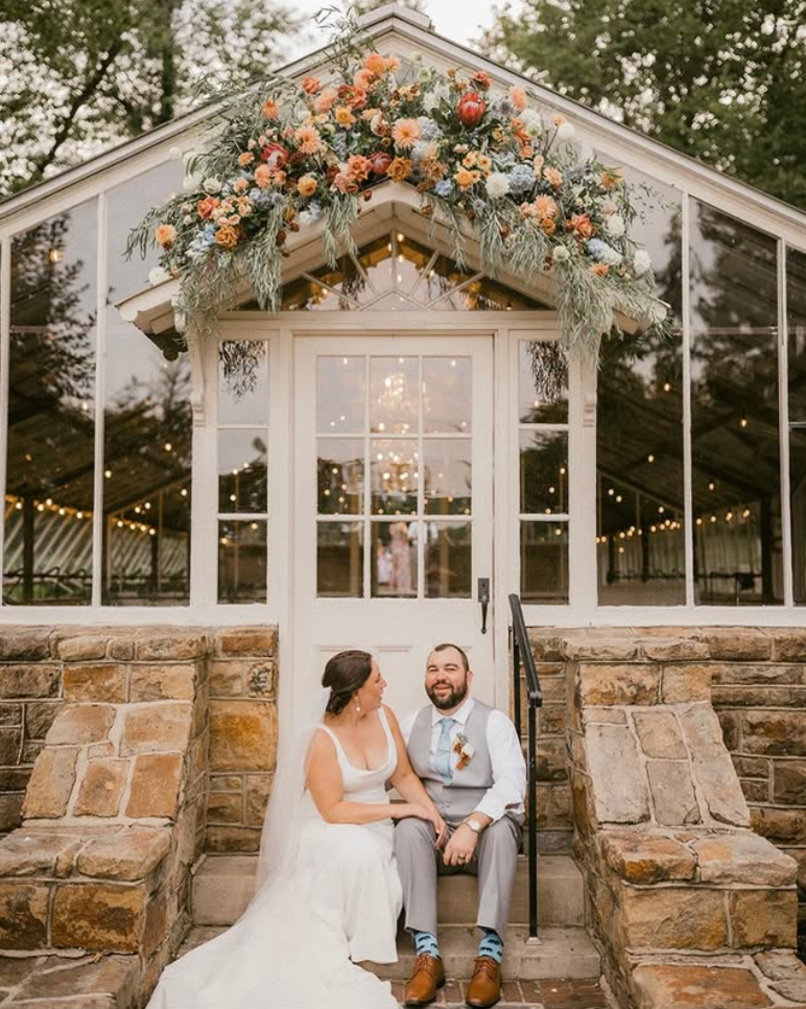 Bride and groom sitting outside the greenhouse reception space at Historic Shady Lane wedding venue