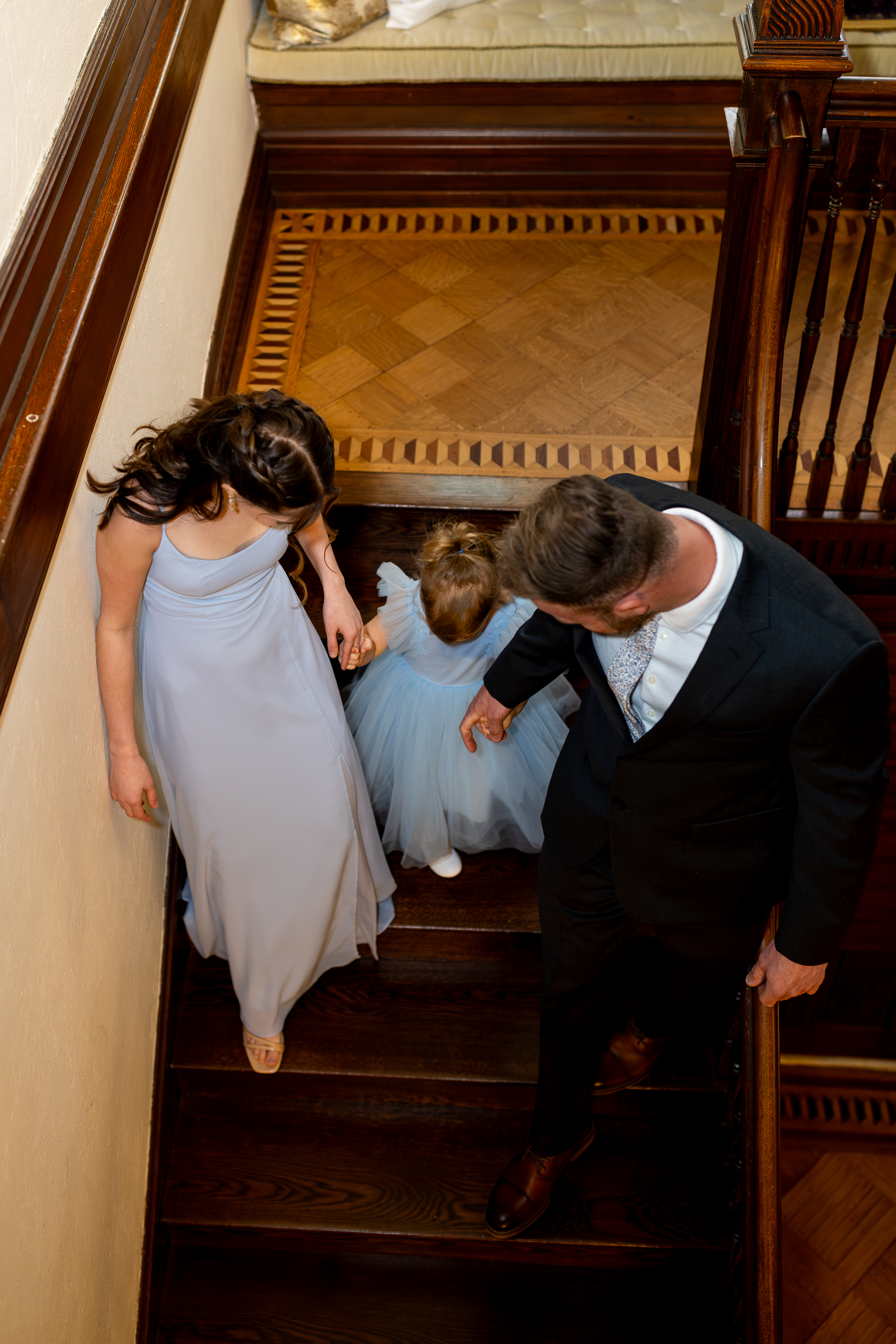 Family Moment During Pennsylvania Elopement Bride's daughters and groom walk down a historic staircase together during a family-focused Pennsylvania elopement.