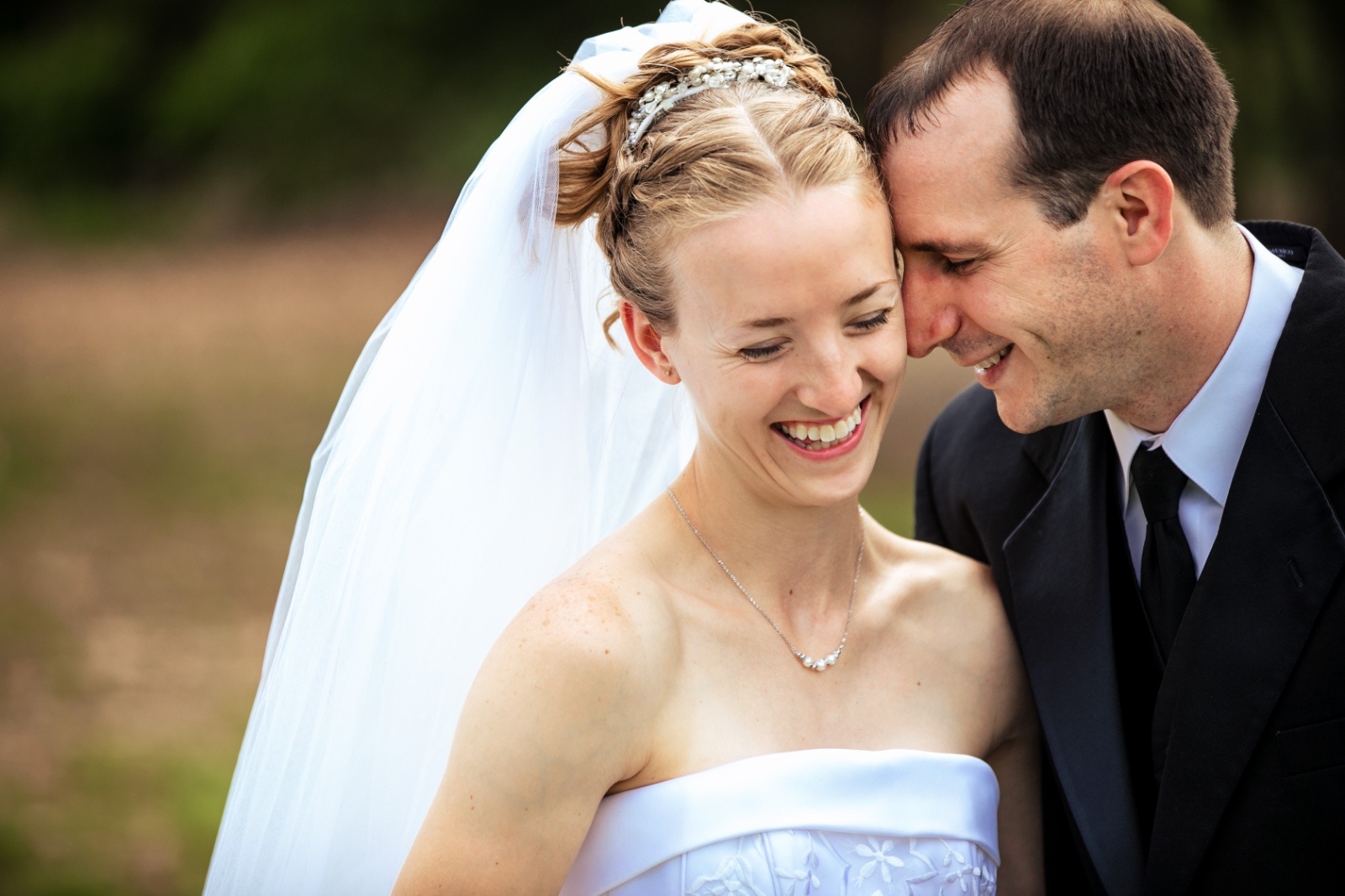 Joyful Wedding Portrait by Kelly Knaub Photography Bride laughs as the groom leans in close during a candid wedding portrait that captures their genuine connection and happiness.