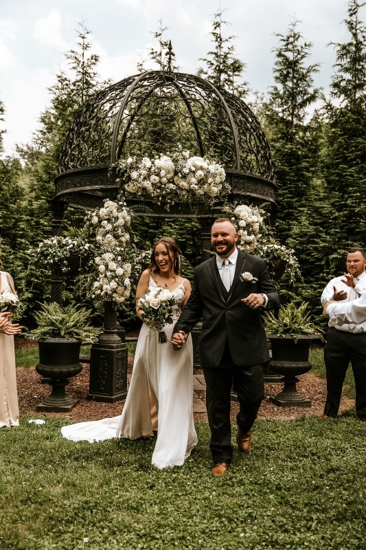 Romantic Garden Micro Wedding Ceremony with Statement Florals Bride and groom walking down the aisle after a garden wedding ceremony beneath an ornate gazebo with lush white floral installations in Central Pennsylvania.