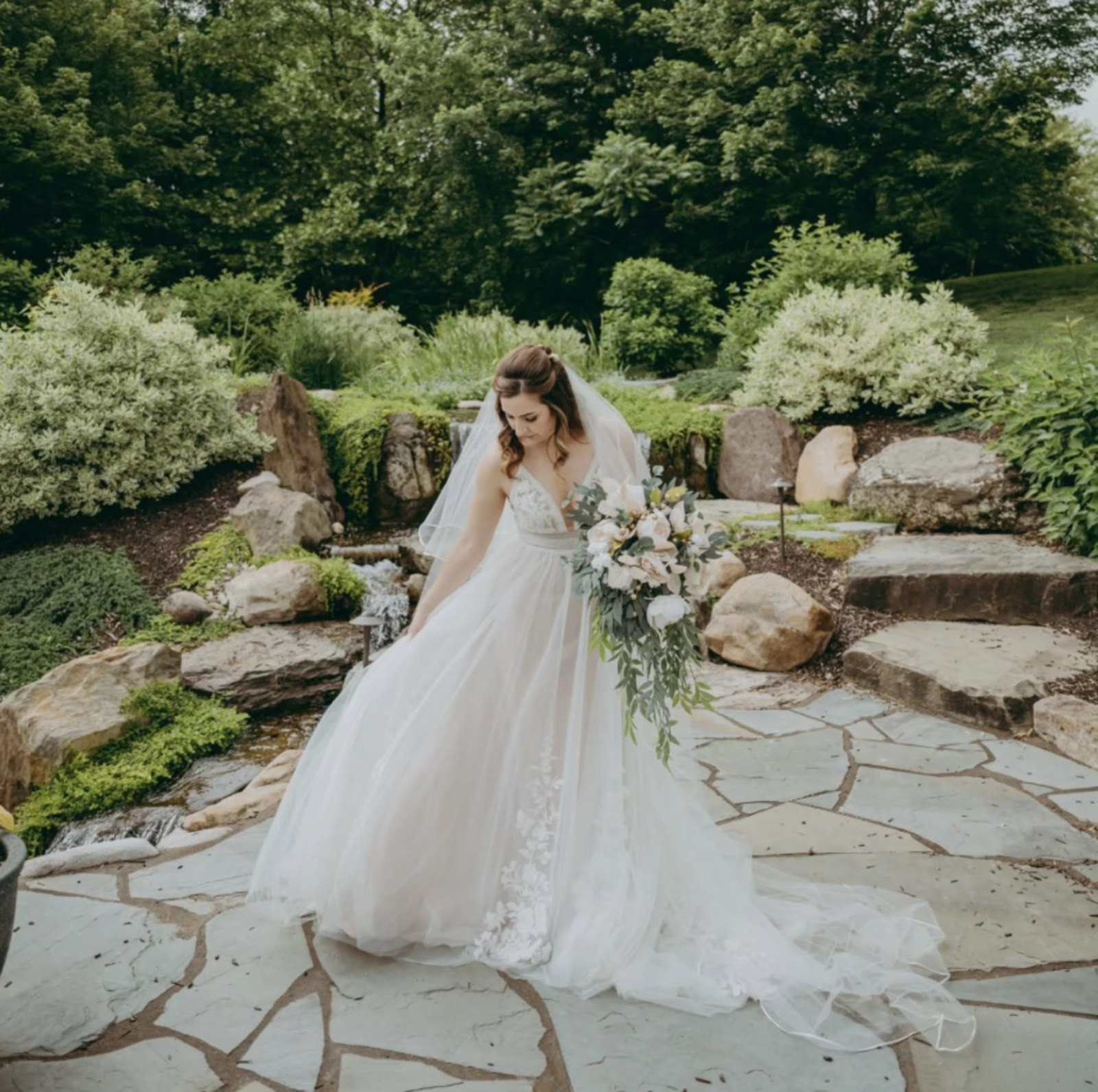 Bride standing in a landscaped garden with waterfall and greenery at a Lancaster PA wedding venue