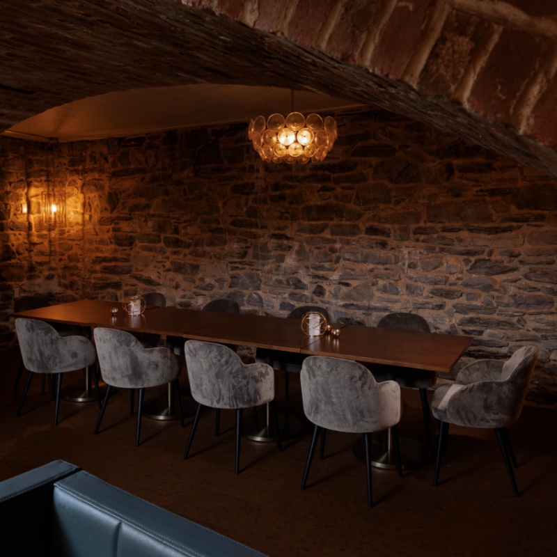 Proof of Lancaster Private Dining Space Private dining area at Proof of Lancaster with a long table, upholstered chairs, exposed stone walls, and warm ambient lighting.