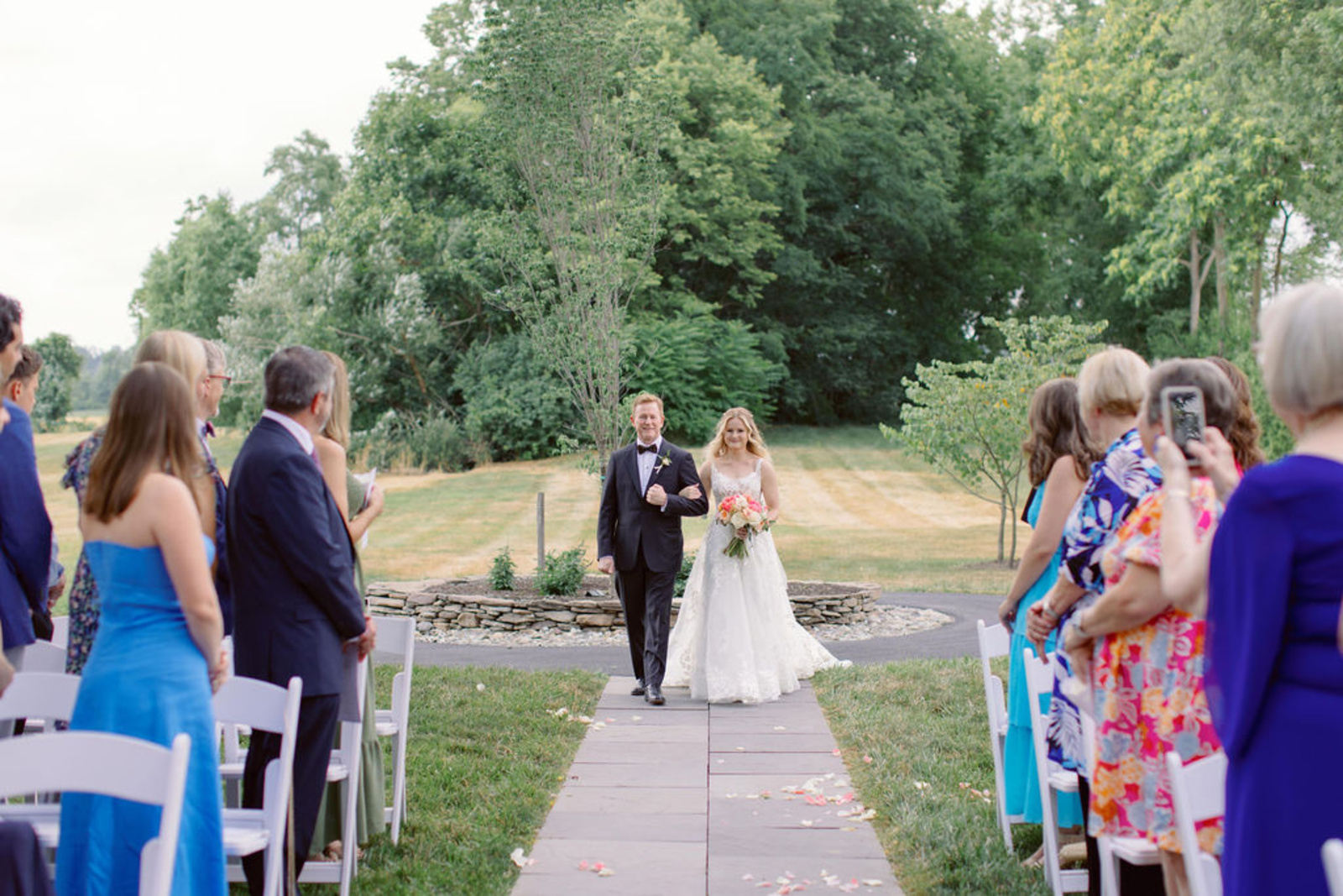 Bride Walking Down the Aisle at Historic Ashland Bride walking down the outdoor ceremony aisle with a family member during her early summer wedding at Historic Ashland in Pennsylvania.