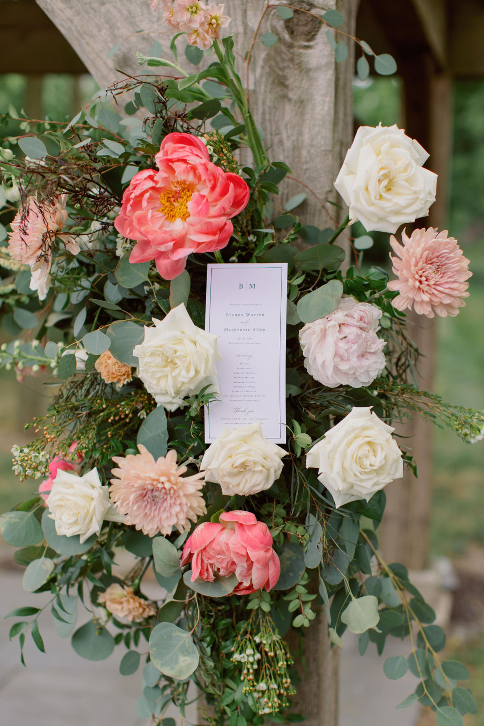 Summer Ceremony Florals at Historic Ashland Coral, blush, peach, and white ceremony florals decorating the wooden pergola during an outdoor wedding ceremony at Historic Ashland.
