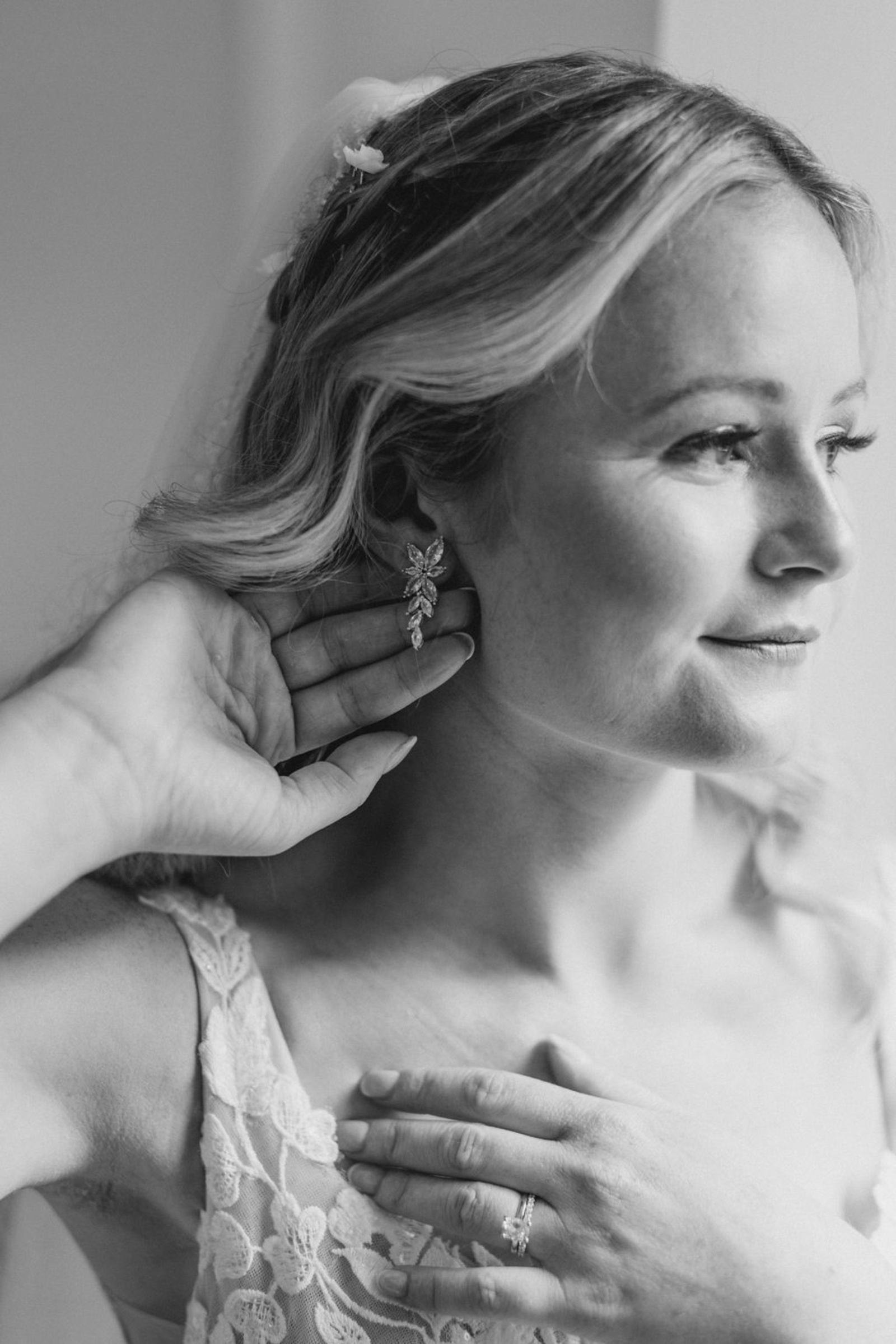 Bride Putting on Earrings Before Ceremony Black-and-white close-up portrait of the bride putting on floral statement earrings before her Historic Ashland wedding ceremony.