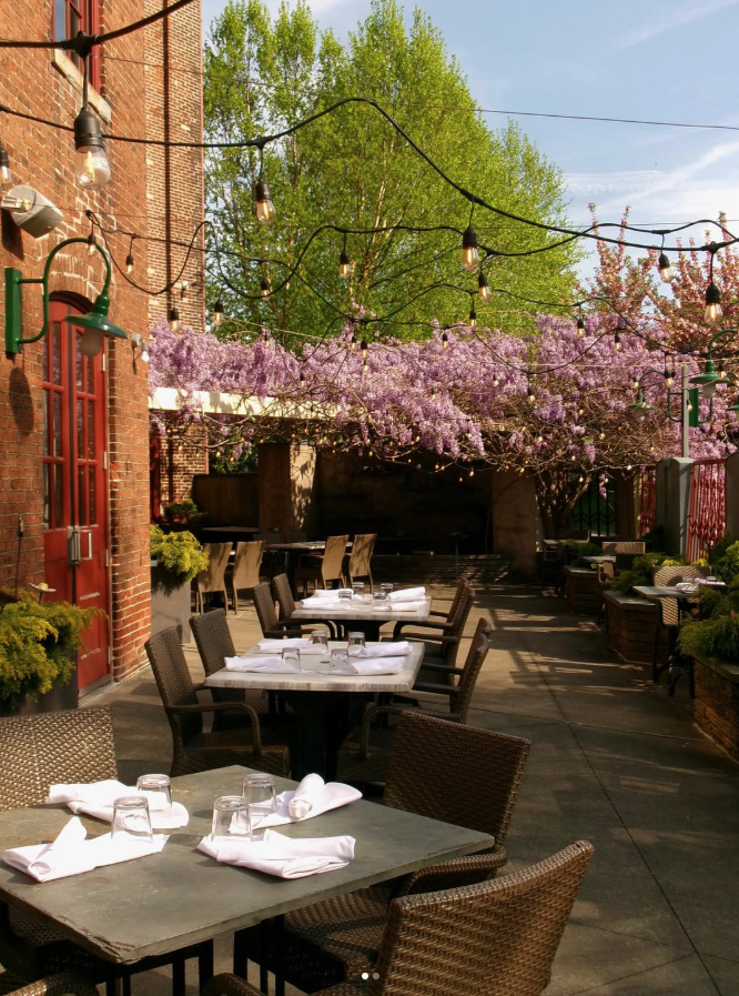 Outdoor patio dining at John J. Jeffries in Lancaster, Pennsylvania, featuring string lights and blooming wisteria, ideal for a rehearsal dinner.