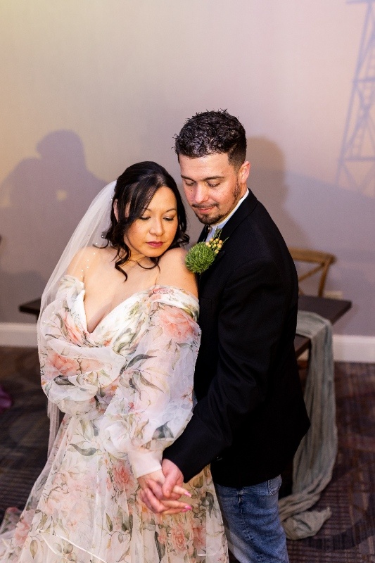 The bride and groom share an intimate moment, holding hands and leaning close beneath soft sunset lighting that captures the rustic romance of this Oklahoma!-inspired wedding shoot.